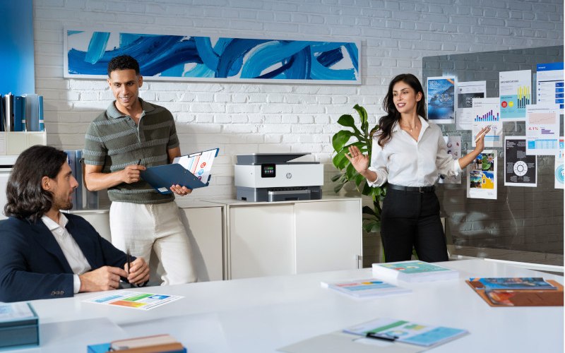 A team in a modern office with a shared HP multifunction printer