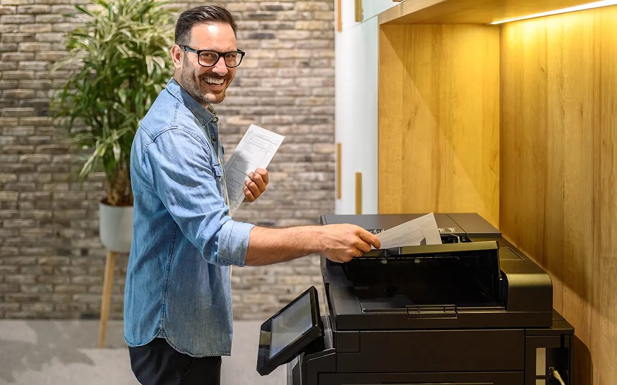 A professional collecting printed documents at a managed office multifunction printer